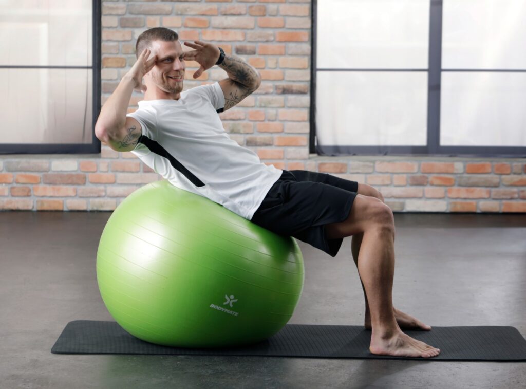 BODYMATE Trainer Martin bei Übung mit grünem Gymnastikball Studioloft